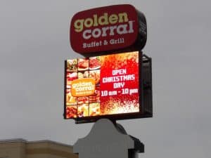A tall sign for Golden Corral Buffet & Grill features the restaurant's logo at the top. Below, it displays images of food and reads "OPEN CHRISTMAS DAY 10 am - 10 pm." Designed by a leading Sign Company in Orange County, the background of the operating hours is red with a snowflake pattern.