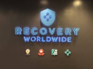 glowing blue sign for medical company on black wall.