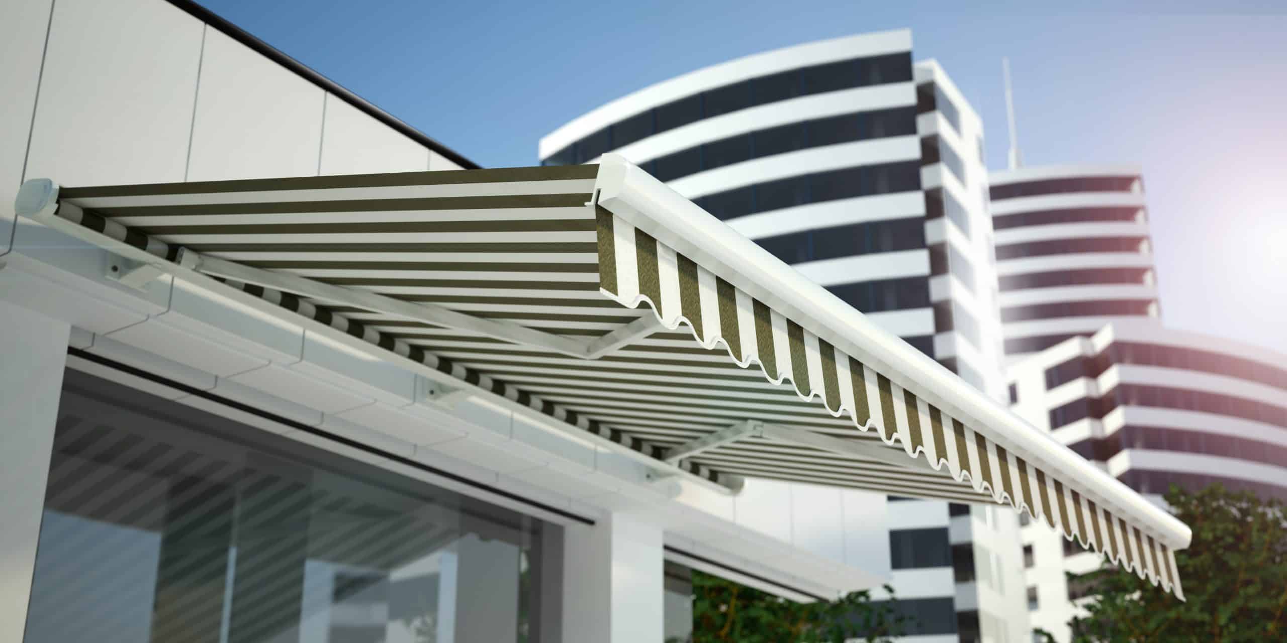 Close-up of a striped retractable awning extended over a glass door or window on a sunny day. In the background, there are modern, tall buildings with curved designs and alternating black and white horizontal stripes. For top-notch visibility in such settings, Custom Sign Services Orange County offer ideal solutions.