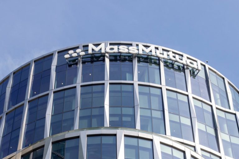 A modern glass building with a rounded facade, crafted by a renowned Sign Company in Orange County, proudly displays the "MassMutual" logo at the top. The sky is clear blue, and the building features several floors with large windows.